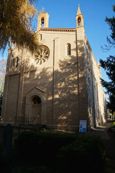 Bornstedter Kirche, Eingangsportal an der Rückseite mit Bäumen im Vordergrund an der Seite