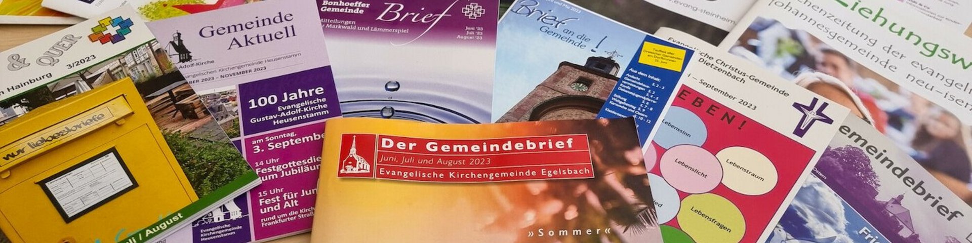Man sieht viele unterschiedliche Gemeindebriefe in verschiedenen Formaten, Farben und Gestaltungen
