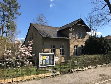 Haus mit Bäumen, Sträuchern und Zaun